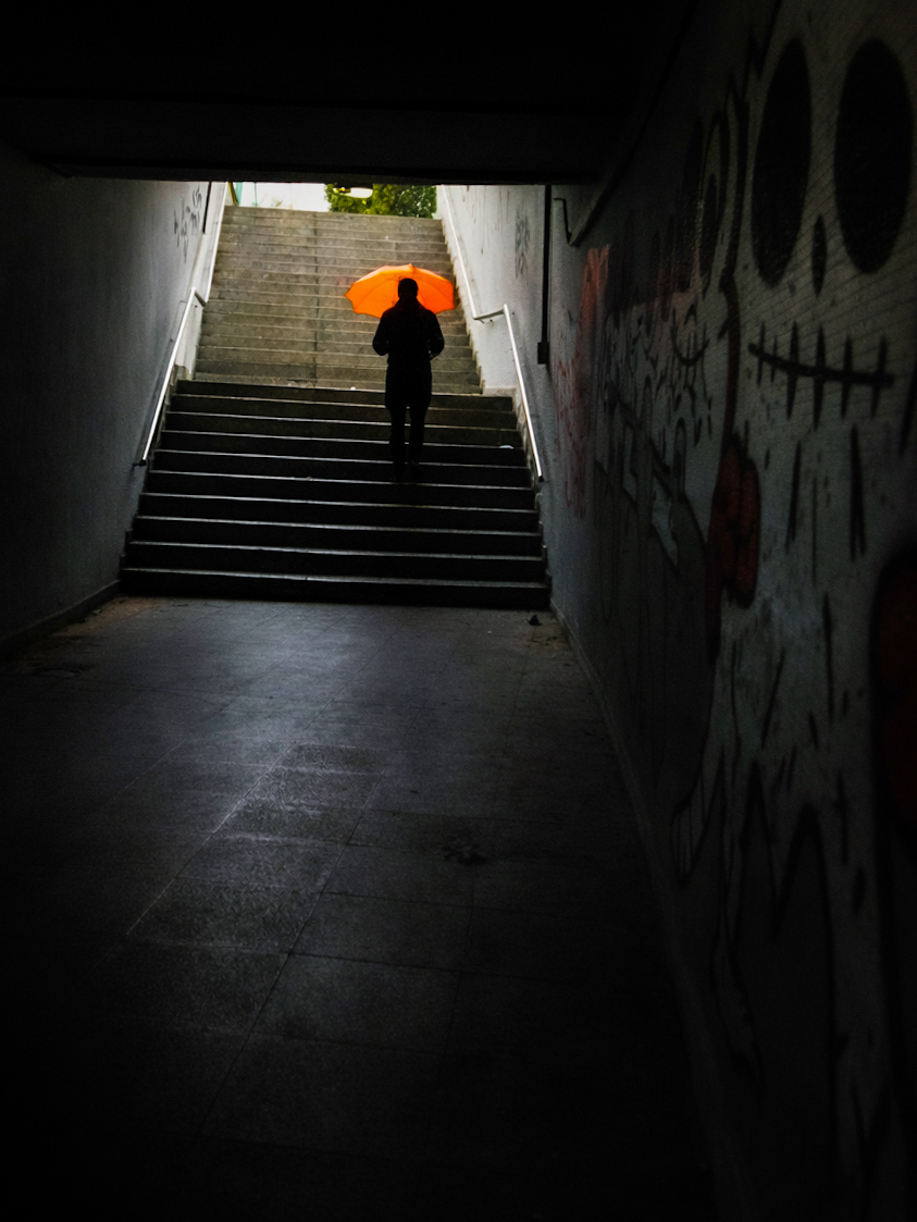 Mann mit orangem Regenschirm